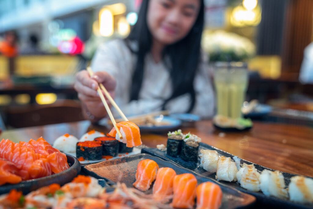 Asian lady eat a Salmon fish sashimi and Sushi in Japanese resta