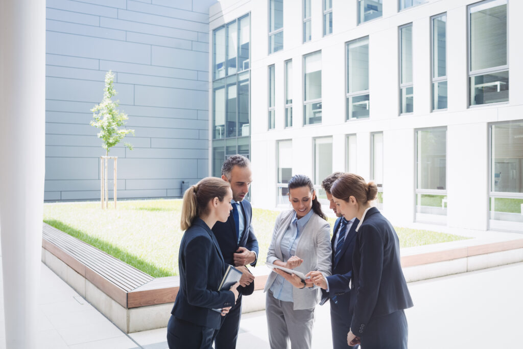 Businesspeople discussing over digital tablet outside office building