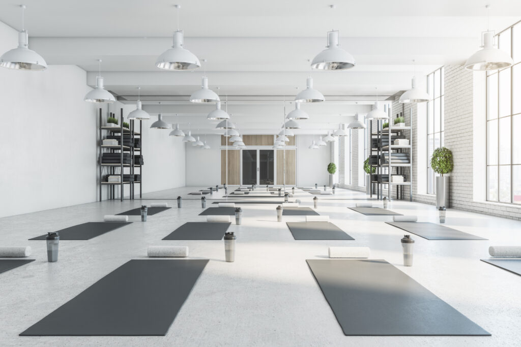 Contemporary bright white yoga studio gym interior with brick wall, window and city view. 3D Rendering.