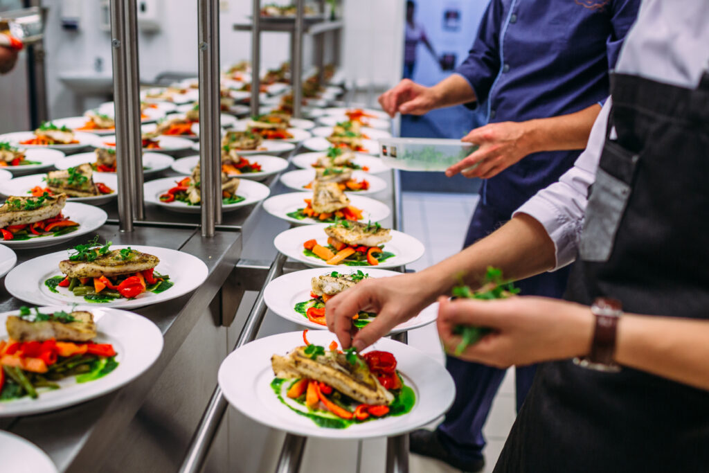 Meat dish with vegetables for catering. Lots of plates.