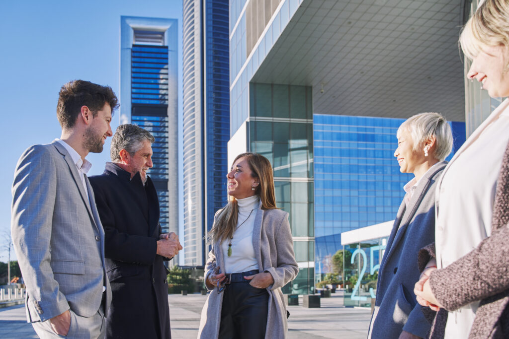 Group of coworkers outside in front of office buildings discuss about business plan.