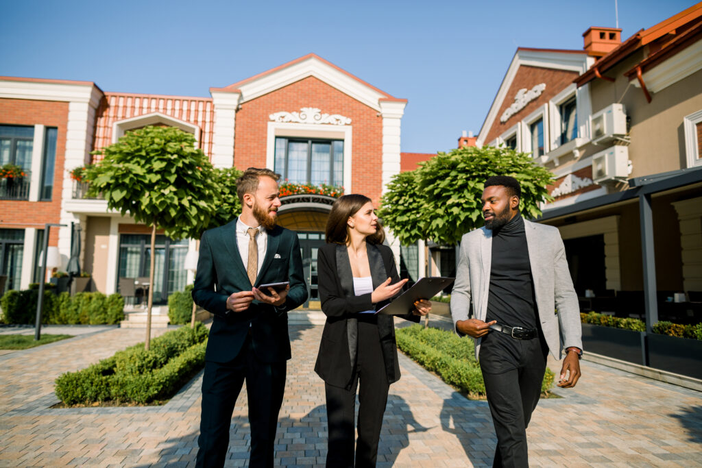 Group of three young multiracial business people, African man and Caucasian man and woman, talking to each other, walking outdoors