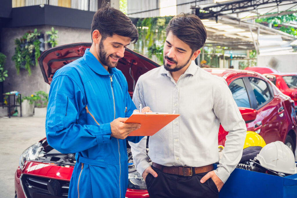 Mechanic holding clipboard with car owner in the workshop garage