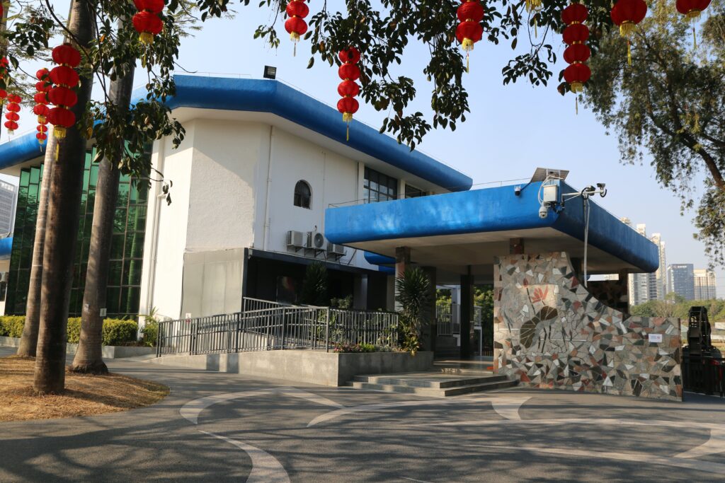 A modern building with blue and white exterior walls, decorated for the Chinese New Year in front of trees on both sides