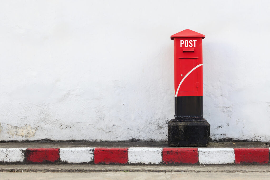 old red postbox on the street. over light