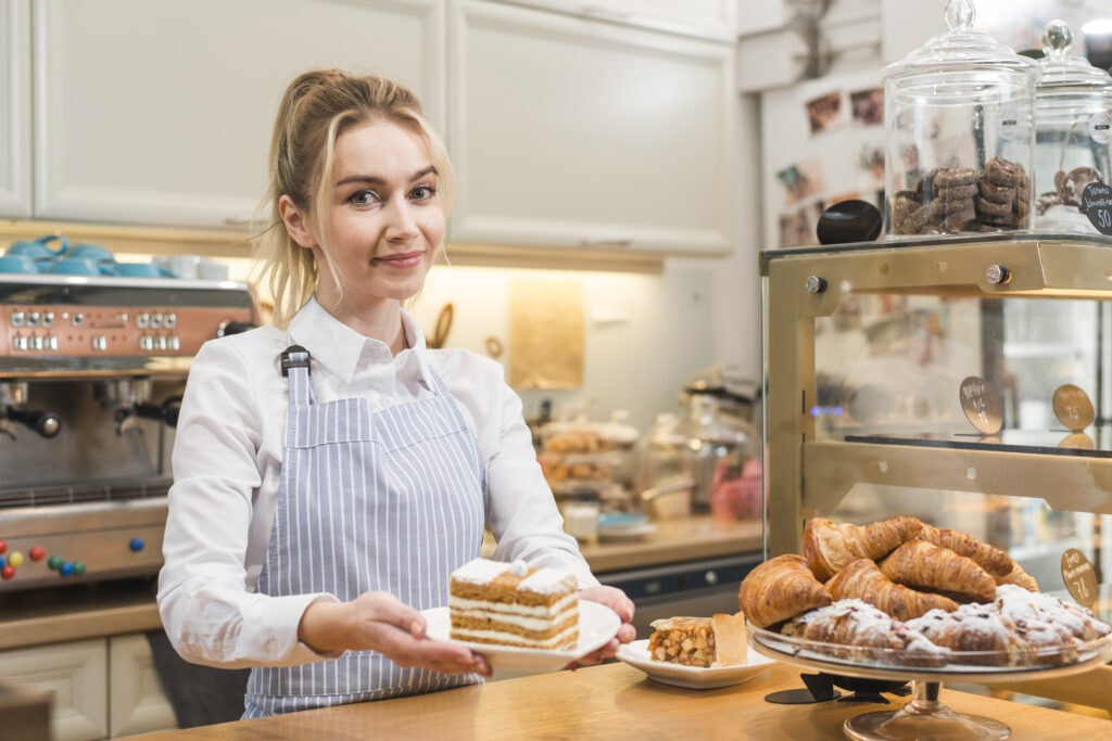portrait-smiling-blonde-young-woman-holding-slice-cake-plate-coffee-shop