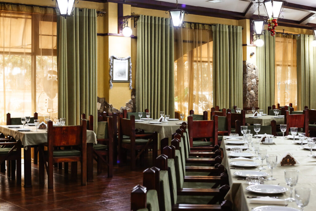 restaurant hall in classic style with green wooden chairs and curtains