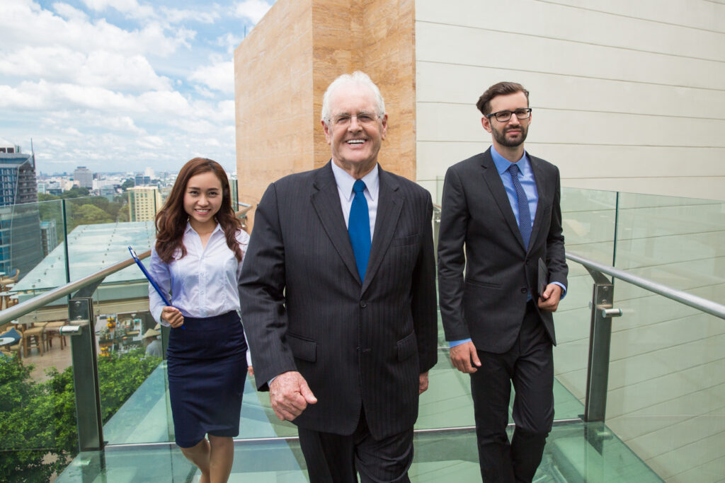 Senior Business Leader with Assistants on Bridge