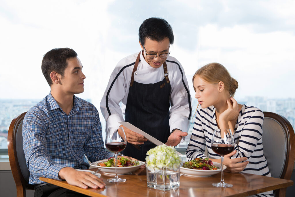 Waiter Offering Couple Main Courses in Restaurant