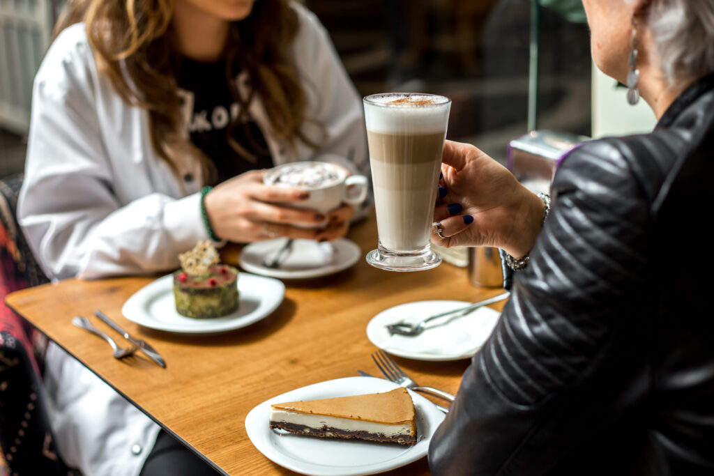 man are drinking coffee with desserts cheesecake and pistachios cake side view