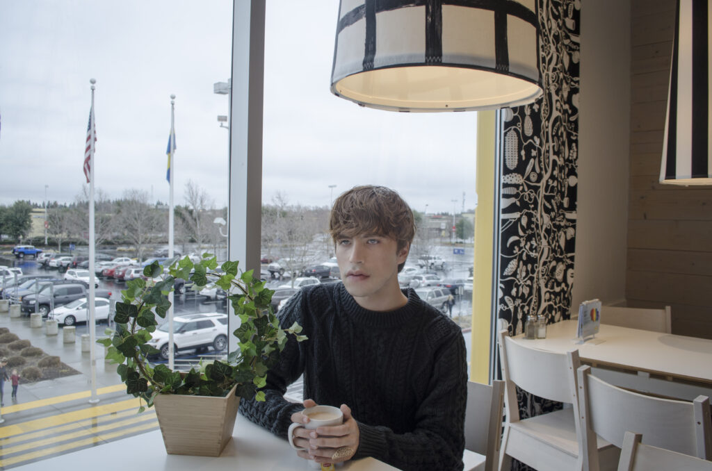 young-man-with-coffee-looking-away-while-sitting-cafe